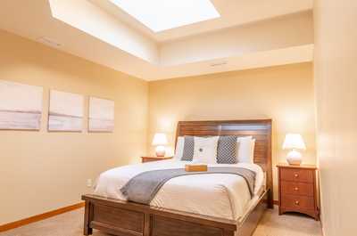 Serene bedroom with tray ceiling, bedside lamps, and crisp white linens.