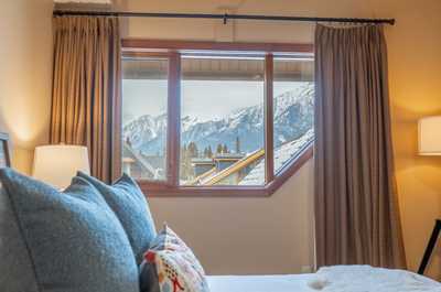 Mountain-view bedroom with large picture window and cozy seating area.