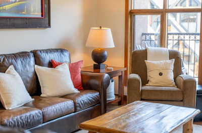 Brown leather couch with white and red pillows near a lamp