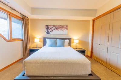Bed with light bedding and artwork above headboard