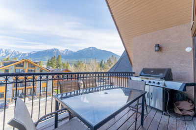 Balcony with table and grill, overlooking mountains and houses
