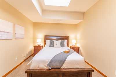 Peaceful bedroom featuring warm tones, soft carpet, and simple modern artwork.