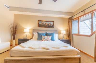 Comfortable bedroom retreat with large windows, ceiling fan, and soft neutral décor.