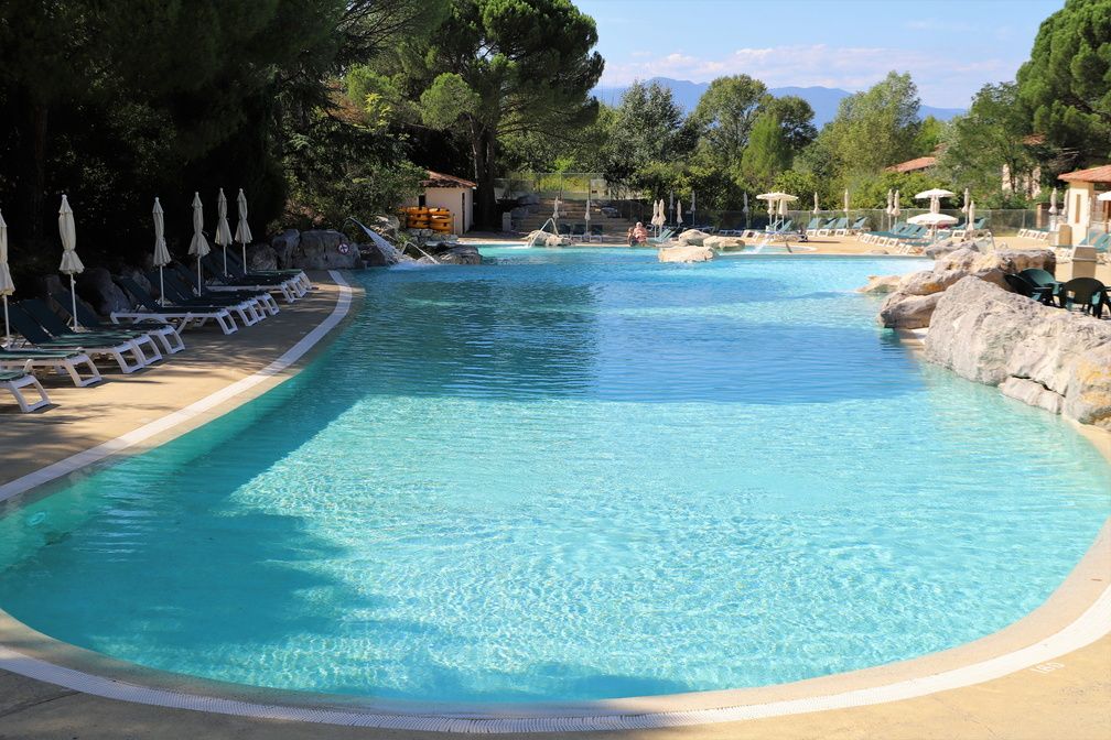 image Guests cooling off in the pool, with the wooded Ardèche hillside rising behind the residence.