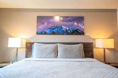 Cozy up in this inviting bedroom featuring a luxurious quilted comforter and warm bedside lighting.