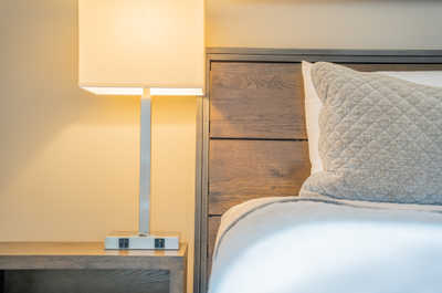 Unwind in style with plush bedding and a warm lamp casting a cozy glow.