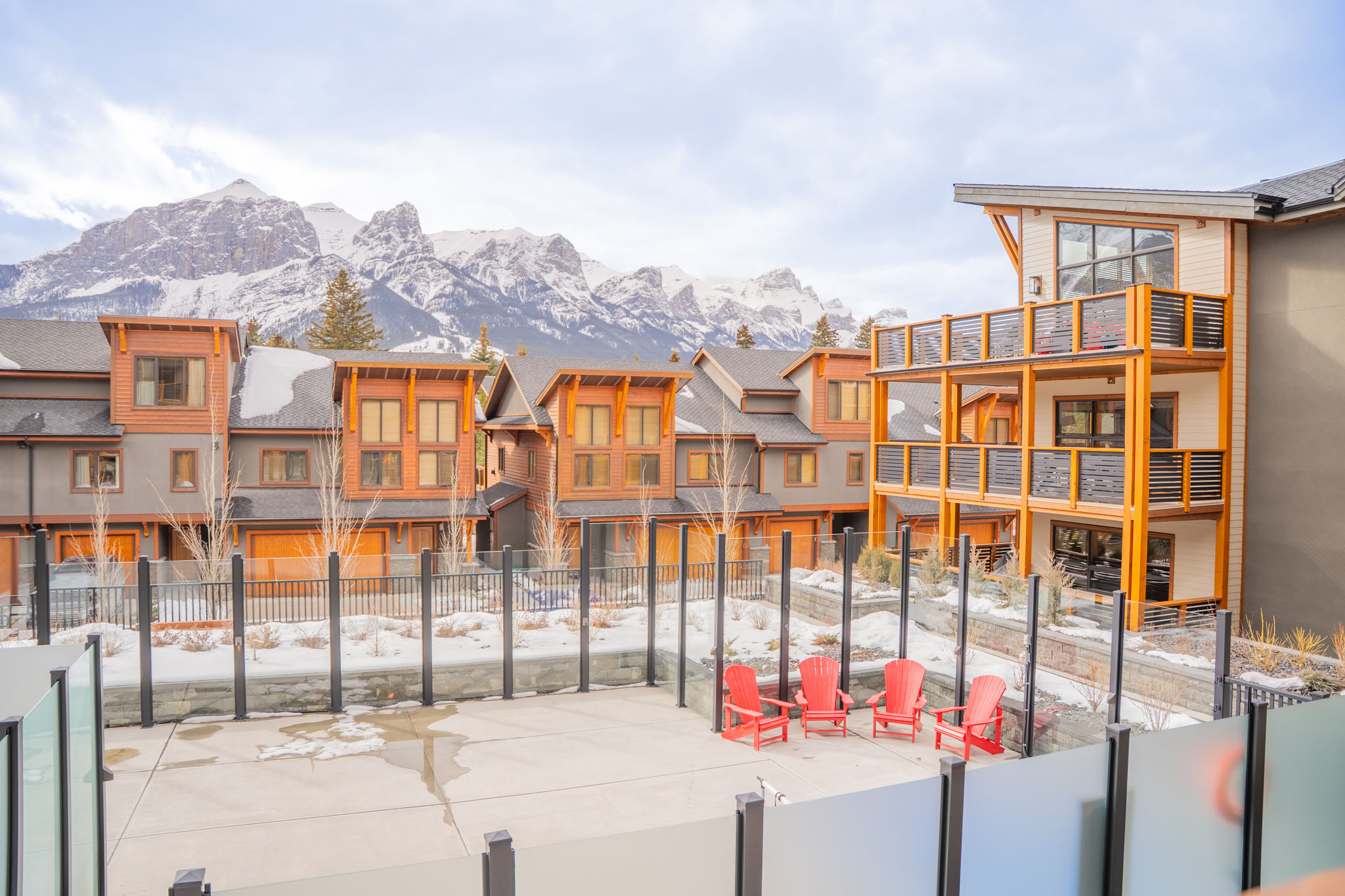 image Step outside to enjoy the inviting outdoor space, complete with vibrant red chairs and a backdrop of majestic peaks.