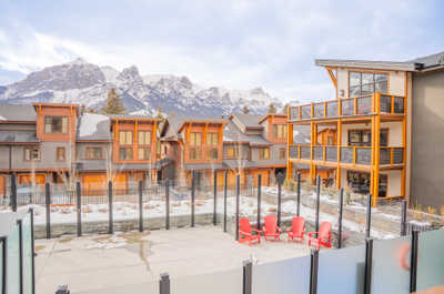 Step outside to enjoy the inviting outdoor space, complete with vibrant red chairs and a backdrop of majestic peaks.