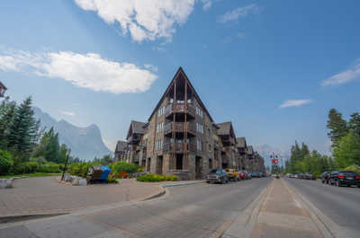 Street view with buildings, parked cars, and mountains in background