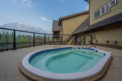 Hot tub area with fencing, buildings, and mountain views