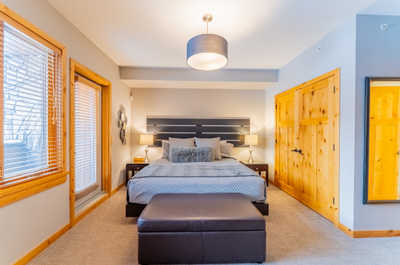 Master bedroom with a bed, lamps, and wooden doors