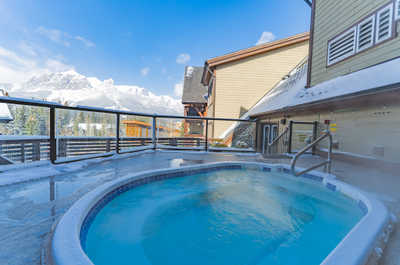 Hot tub with steam and mountain and building views