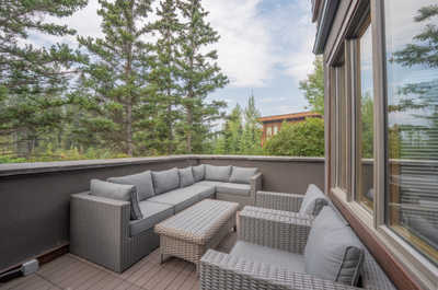 Outdoor seating area with gray furniture and surrounding trees