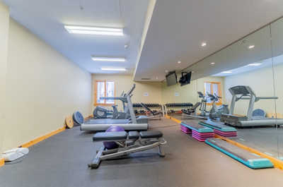 Shared exercise room with weights, equipment, and mirrored wall