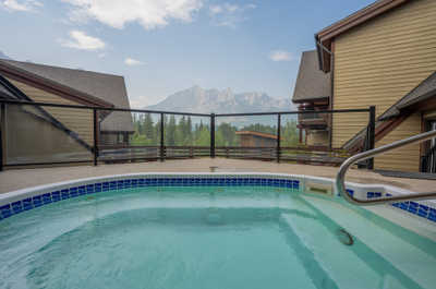 Hot tub on deck with mountains and trees visible in background