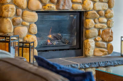 Stone fireplace with a lit flame and surrounding decor