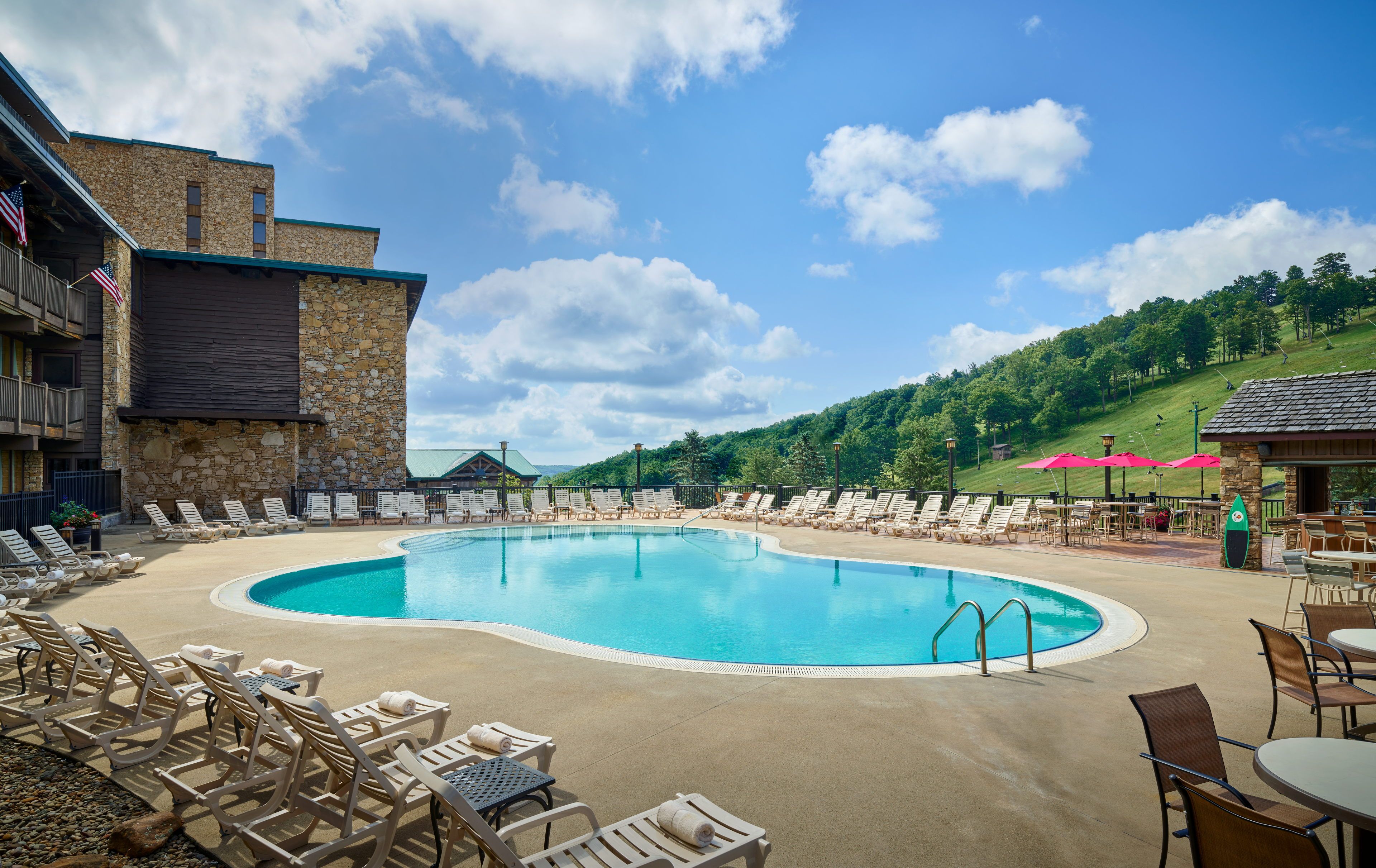 image The pool area offers a refreshing escape, surrounded by sunlit hills and comfy lounge chairs, perfect for unwinding in a cozy mountain atmosphere.