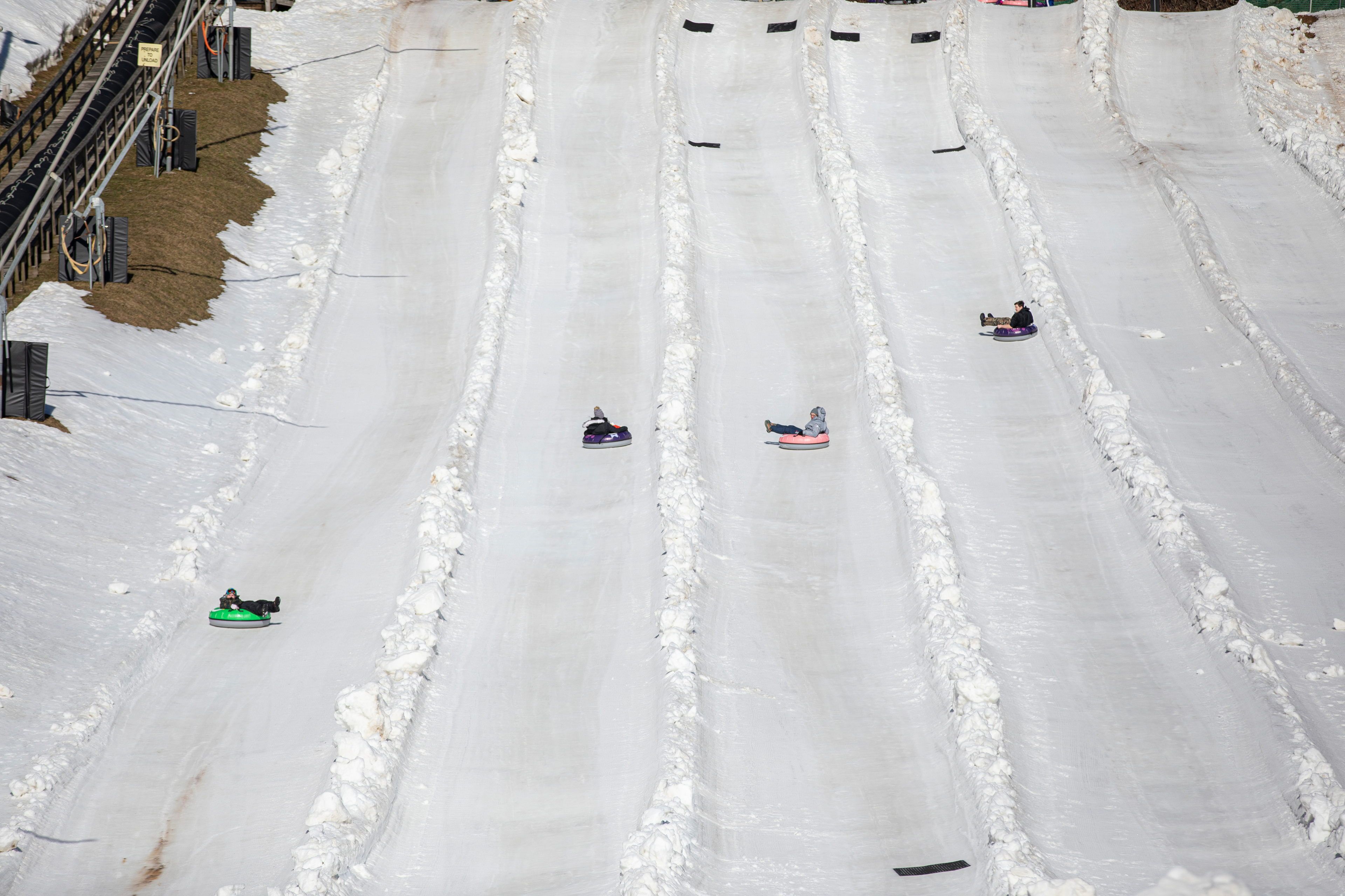 image Colorful tubes glide down snowy slopes, with delighted riders enjoying the crisp mountain air and the thrill of winter fun under a bright sky.