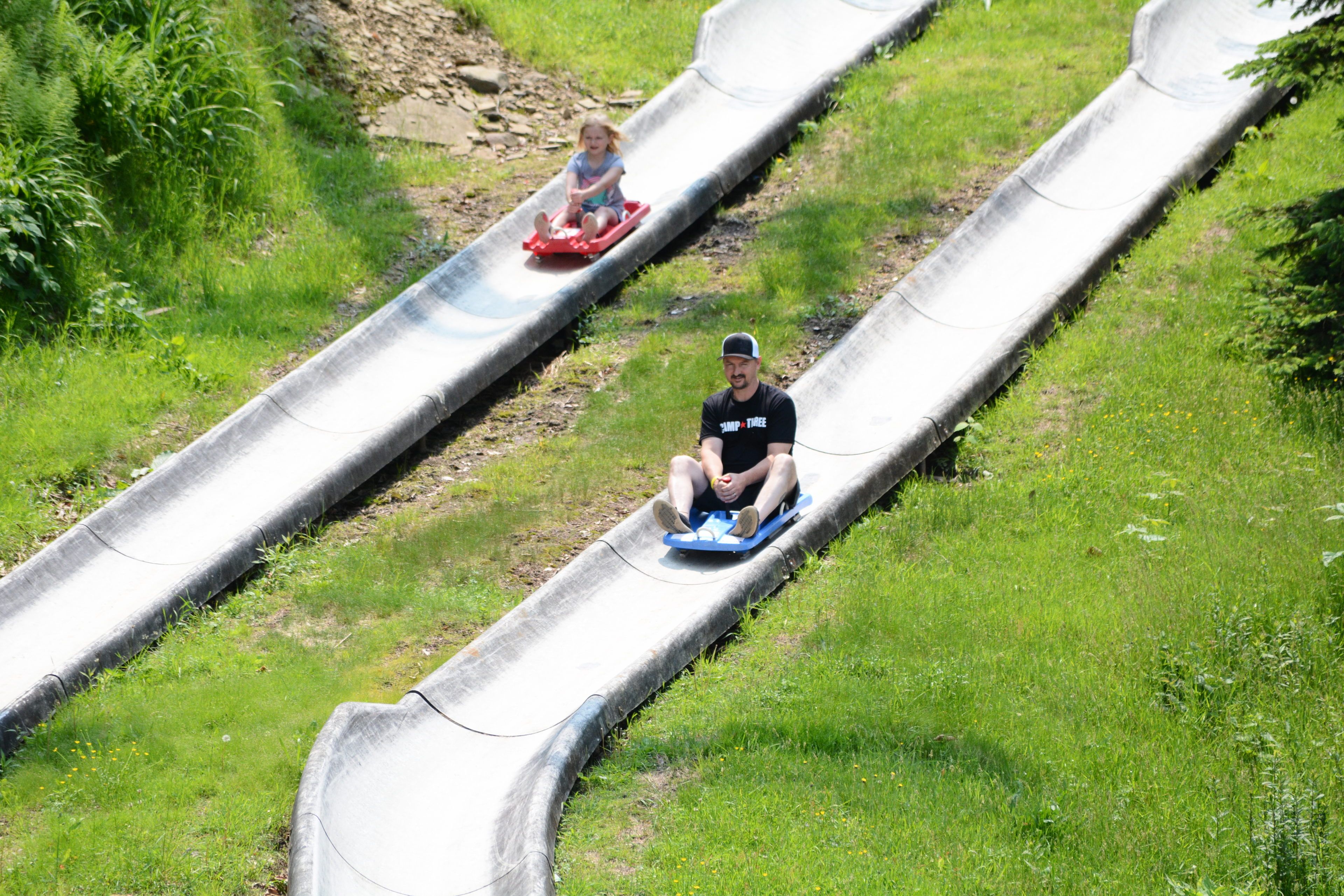 image Amidst the verdant hills, laughter and joy resonate as families enjoy thrilling summer rides down scenic slides.