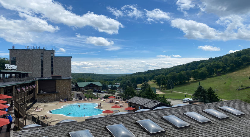 image A panoramic view reveals the vibrant blue pool nestled against rolling hills and a bright sky.