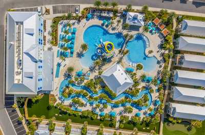 Aerial view of a vibrant resort oasis, featuring sprawling pools and lush tropical landscaping.
