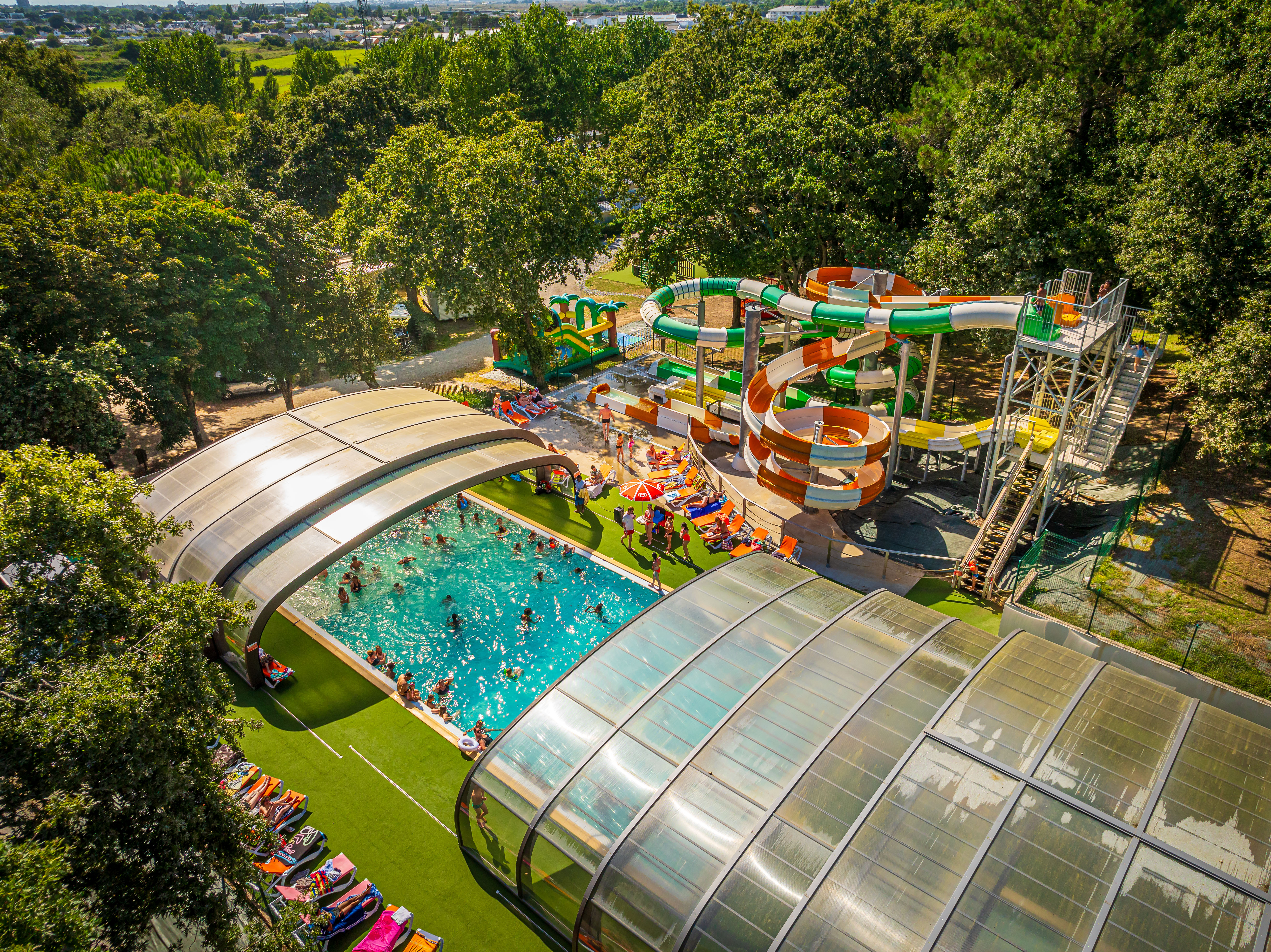 image Dive into fun at Les Ajoncs d’Or, where families enjoy a vibrant outdoor pool surrounded by exciting water slides for all ages.