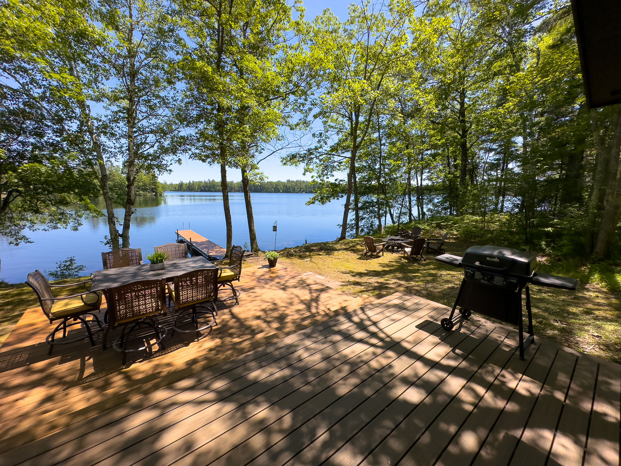 image Dine al fresco on the spacious deck overlooking the lake, equipped with a BBQ grill and plenty of seating for outdoor meals.