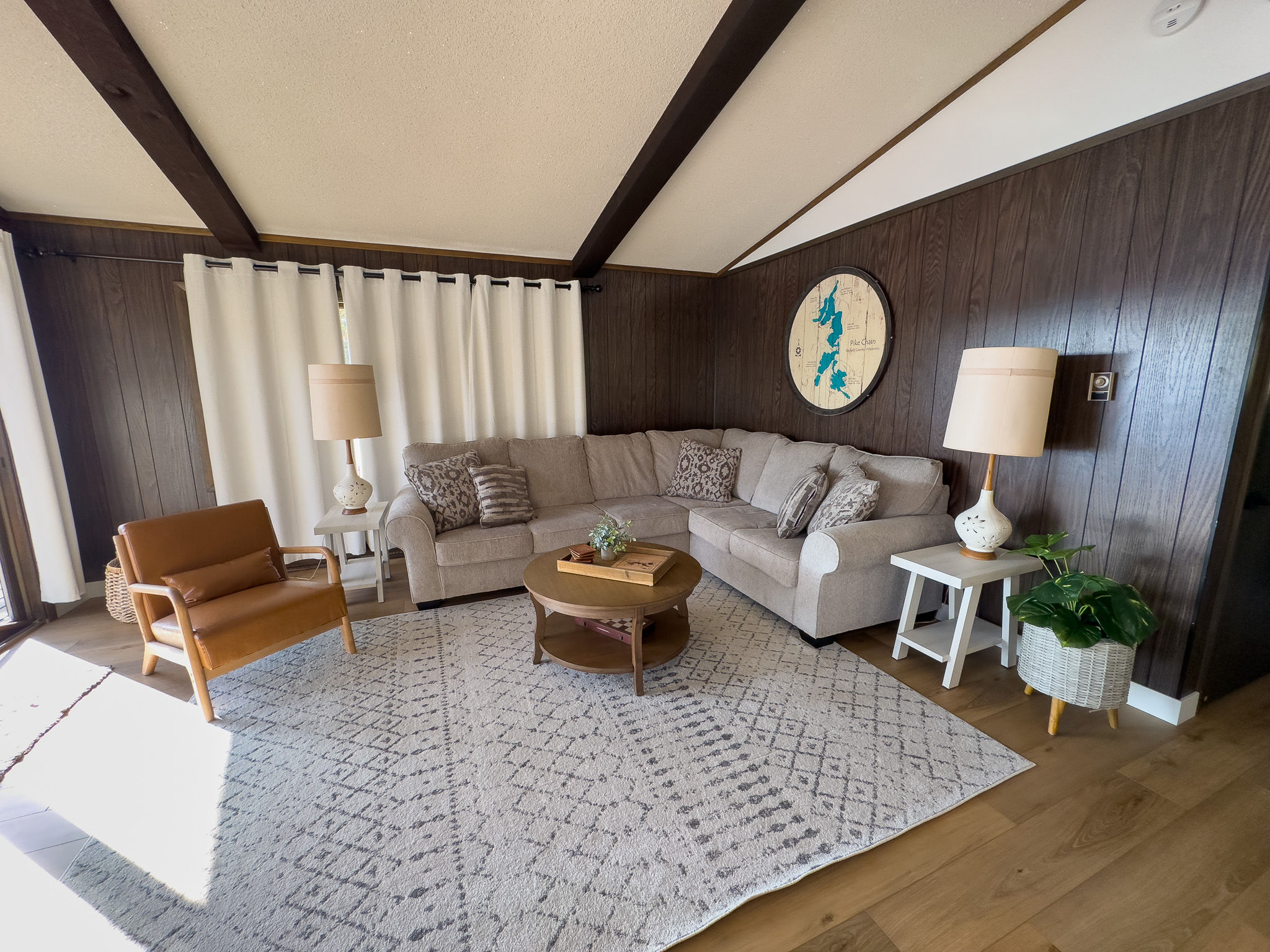 image Relax in the spacious living room featuring comfortable seating, a smart TV, and large windows with views of the surrounding nature.