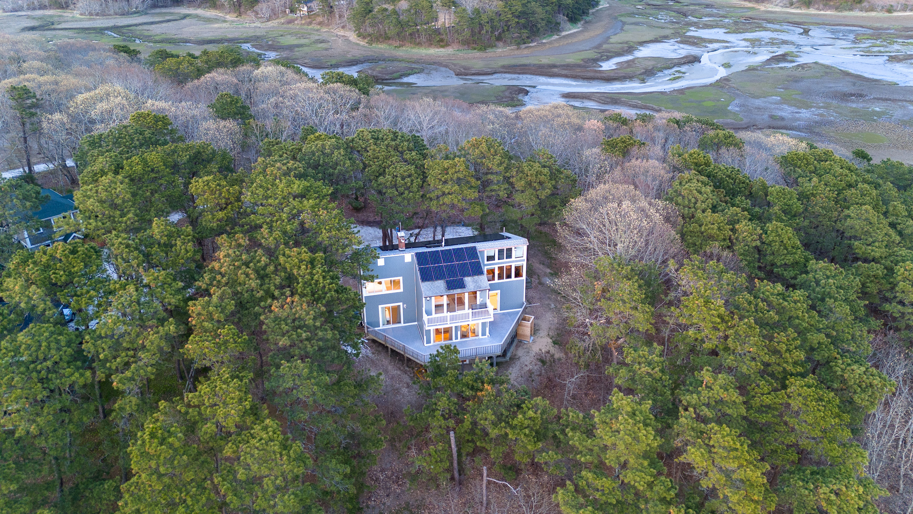 image Aerial view of the charming 5-bedroom home nestled in lush greenery, offering stunning water views and a serene setting.