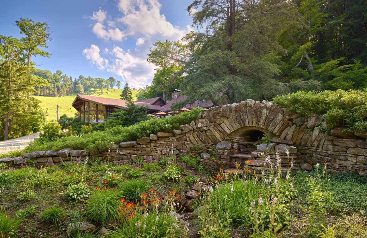 image Picturesque stone bridge surrounded by vibrant greenery and blooming flowers, offering a fairytale-like setting.
