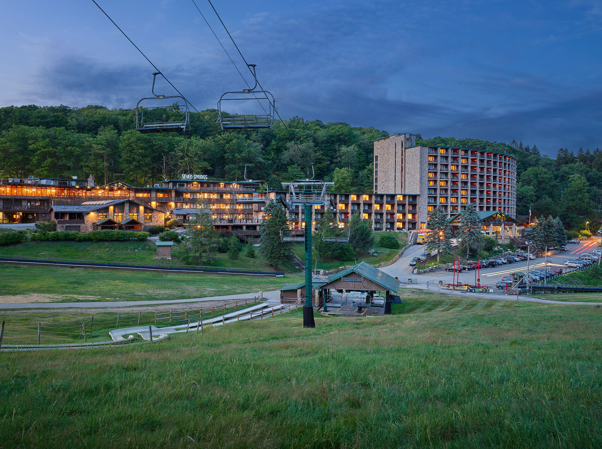 image Scenic view of the property at dusk, with ski lifts and cozy accommodations illuminated against a peaceful mountain backdrop.