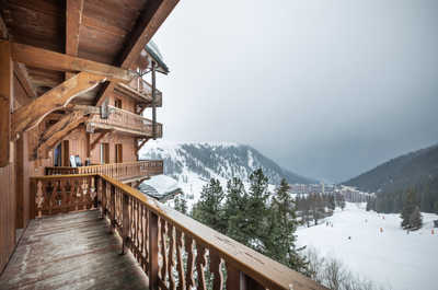 Take in the serene mountain views and fresh alpine air from this cosy wooden balcony, a peaceful escape surrounded by snowy peaks.