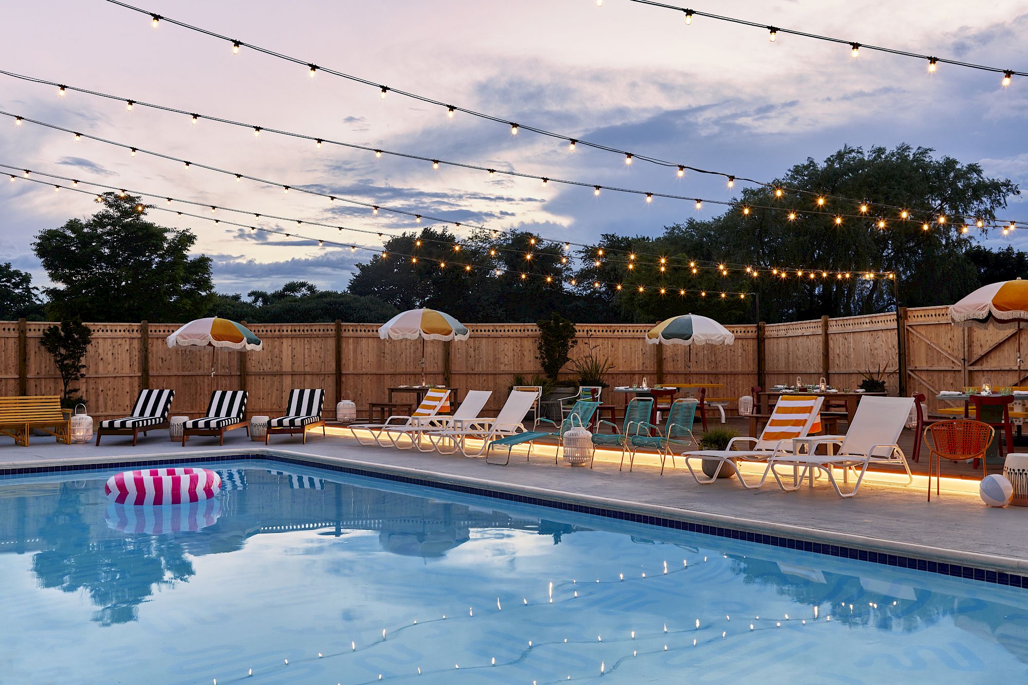 image Beneath a twinkling canopy of lights, relax by the inviting poolside, where vibrant colors and playful umbrellas create a serene retreat perfect for unwinding.
