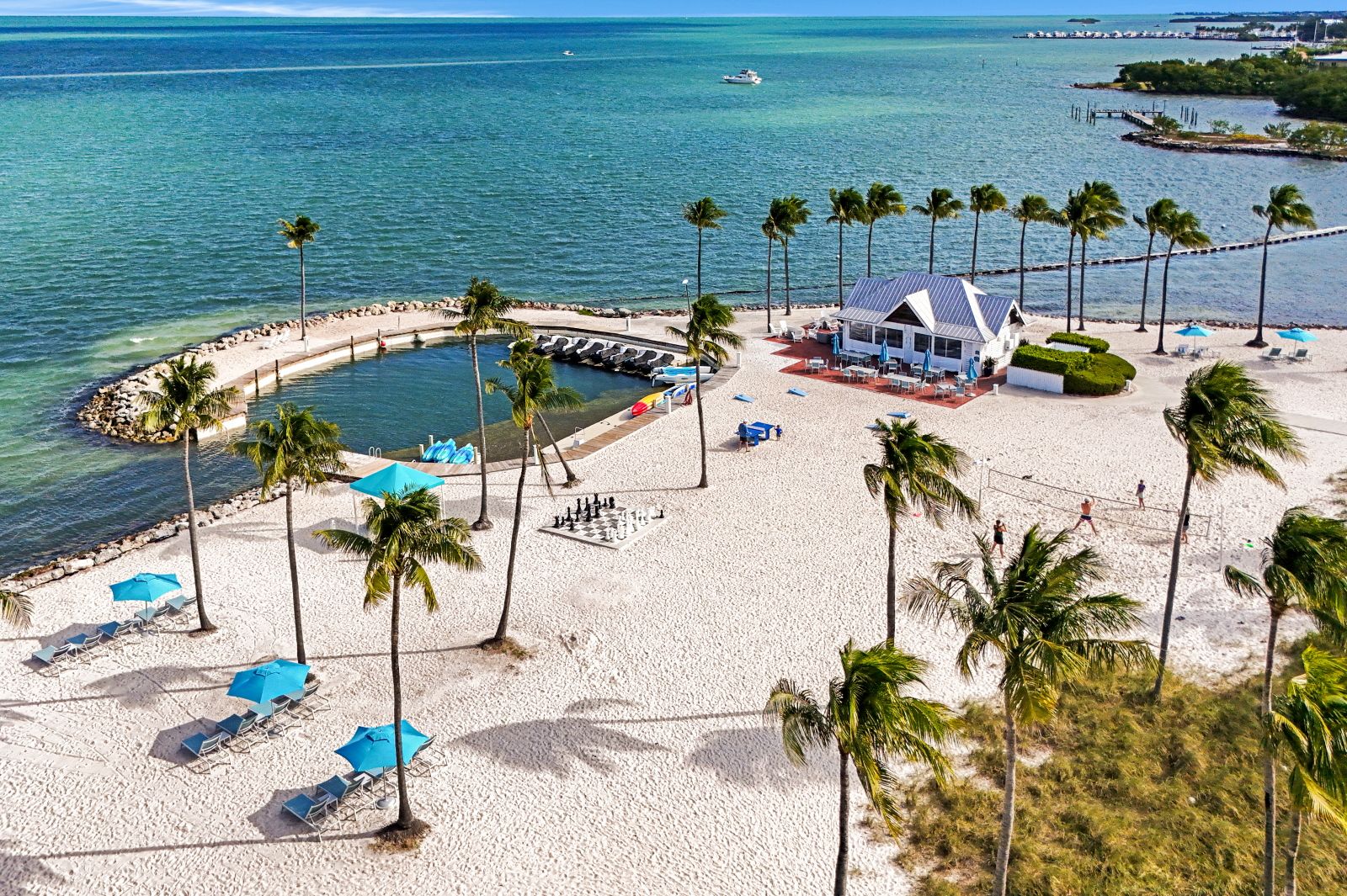 image Aerial view of the resort's white-sand beachfront, calm swimming lagoon, swaying palms, and turquoise Gulf waters.