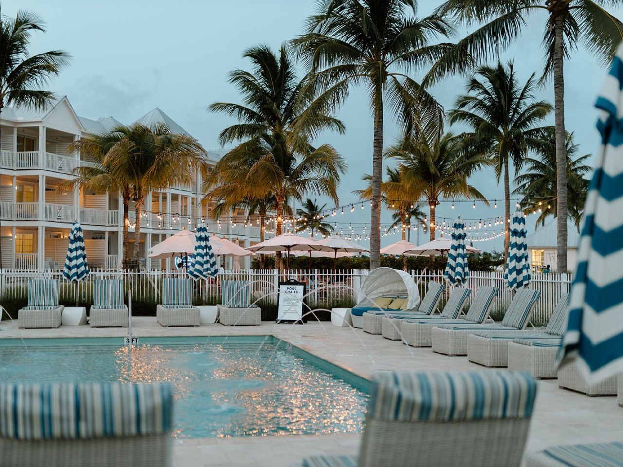 image Cozy seating by the poolside invites you to relax amidst swaying palms and evening ambiance.