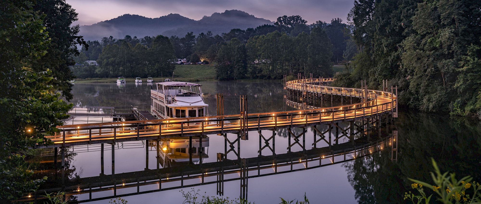 image Twilight settles over the marina as lights reflect on the lake, setting a magical tone for the evening.