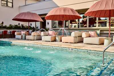 Drift into leisure under blush-toned shade as soft splashes echo the rhythm of a relaxed Charleston day.