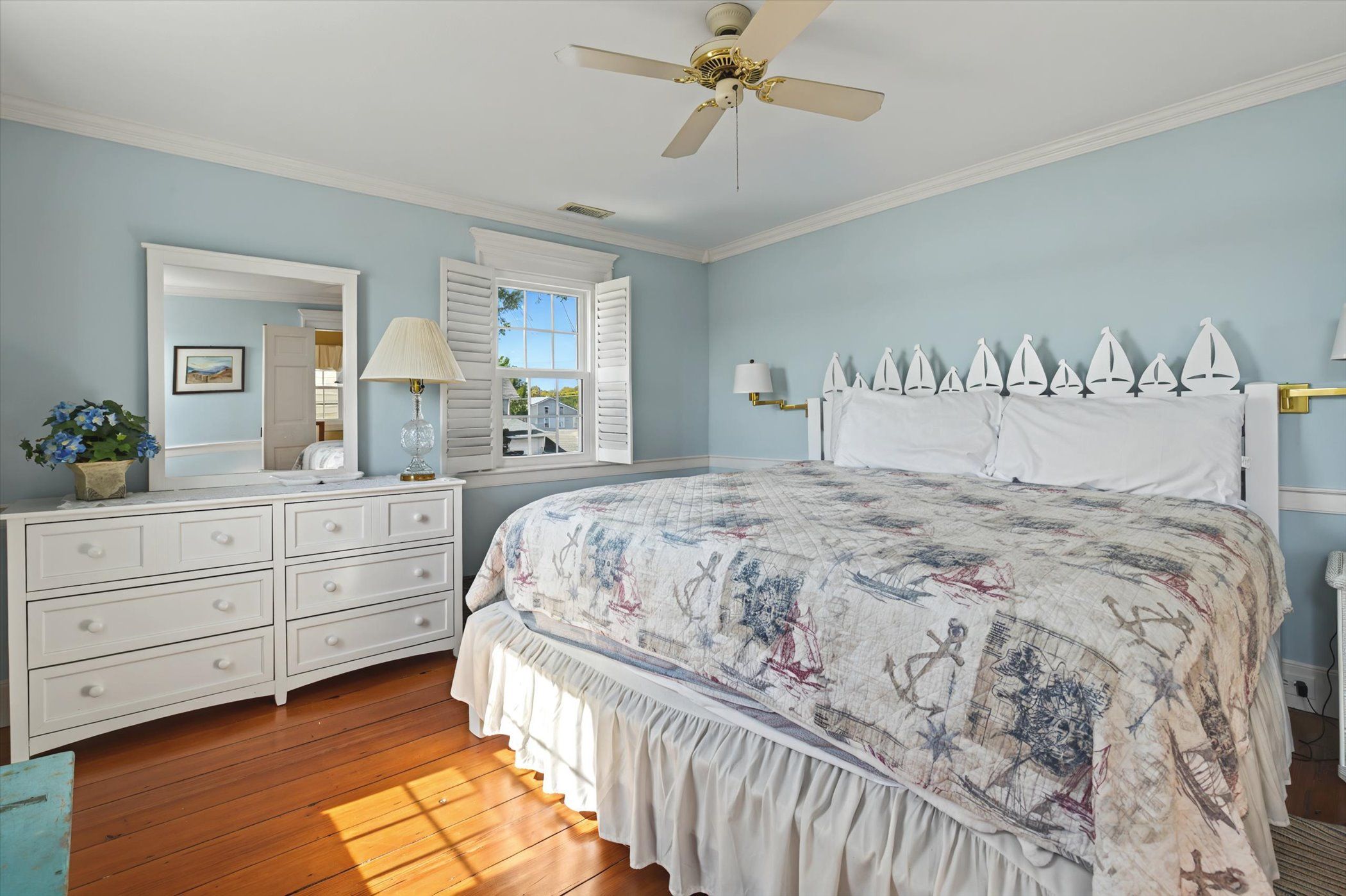 image Serene bedroom with queen bed, dresser, and large windows letting in natural light.
