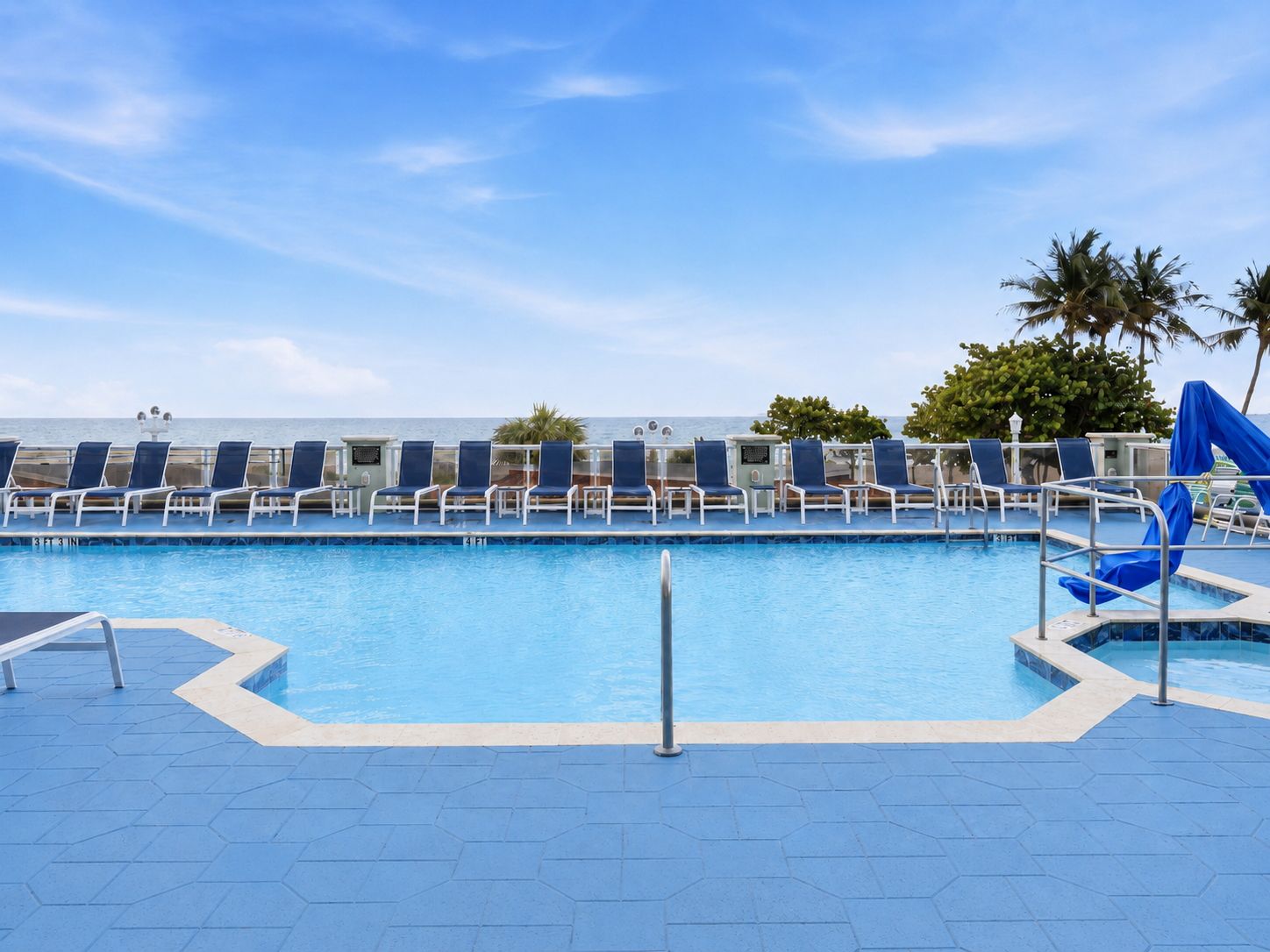 image Swimming pool area with lounge chairs, ocean in background