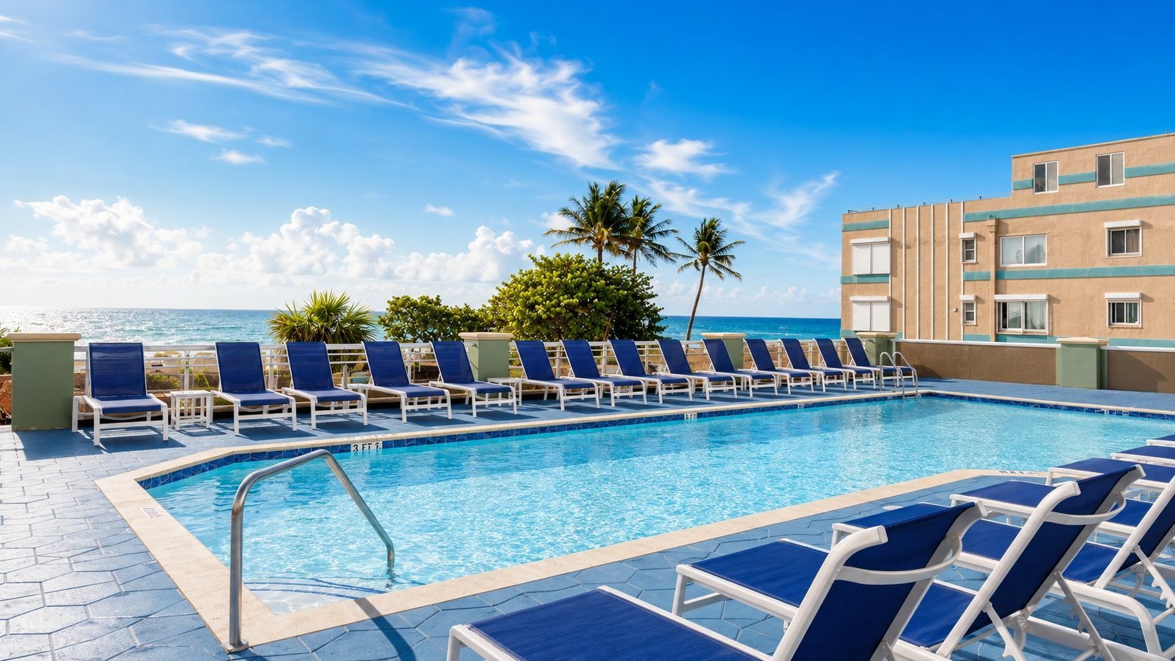 image Swimming pool with lounge chairs, ocean view, and palm trees