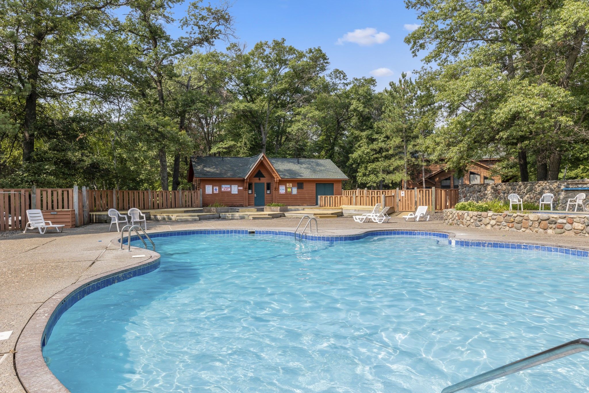 image Refreshing outdoor pool surrounded by lush greenery and a cozy cabin.