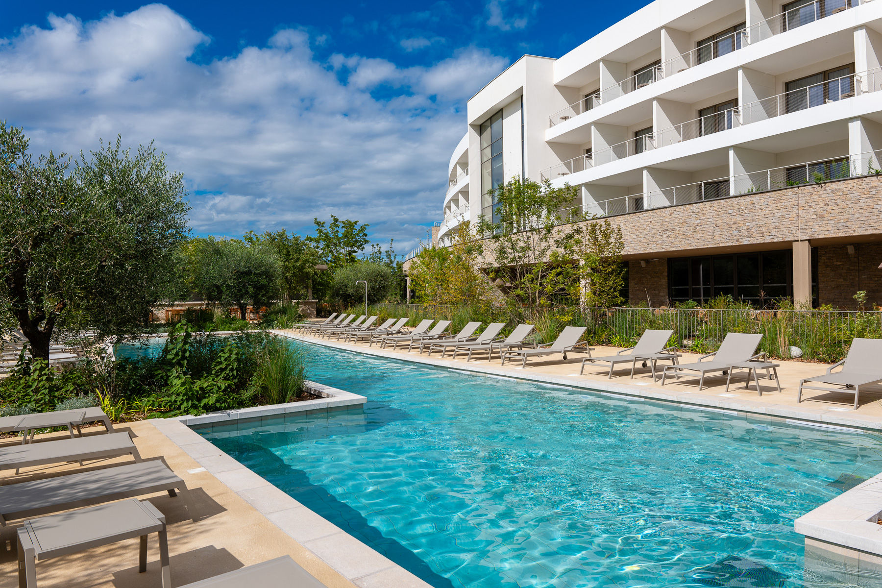 image Enjoy the peaceful ambiance of the resort’s main pool, framed by olive trees and landscaped gardens.