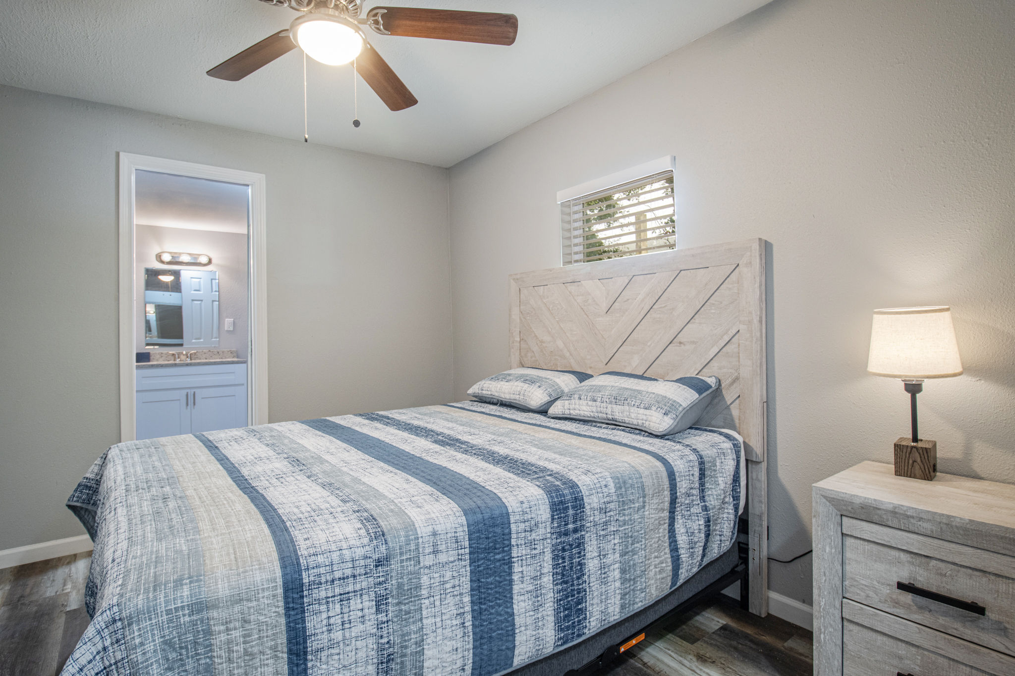 image Unwind in the comfort of this beautifully decorated bedroom, featuring modern decor and a connection to an en-suite bathroom for convenience.