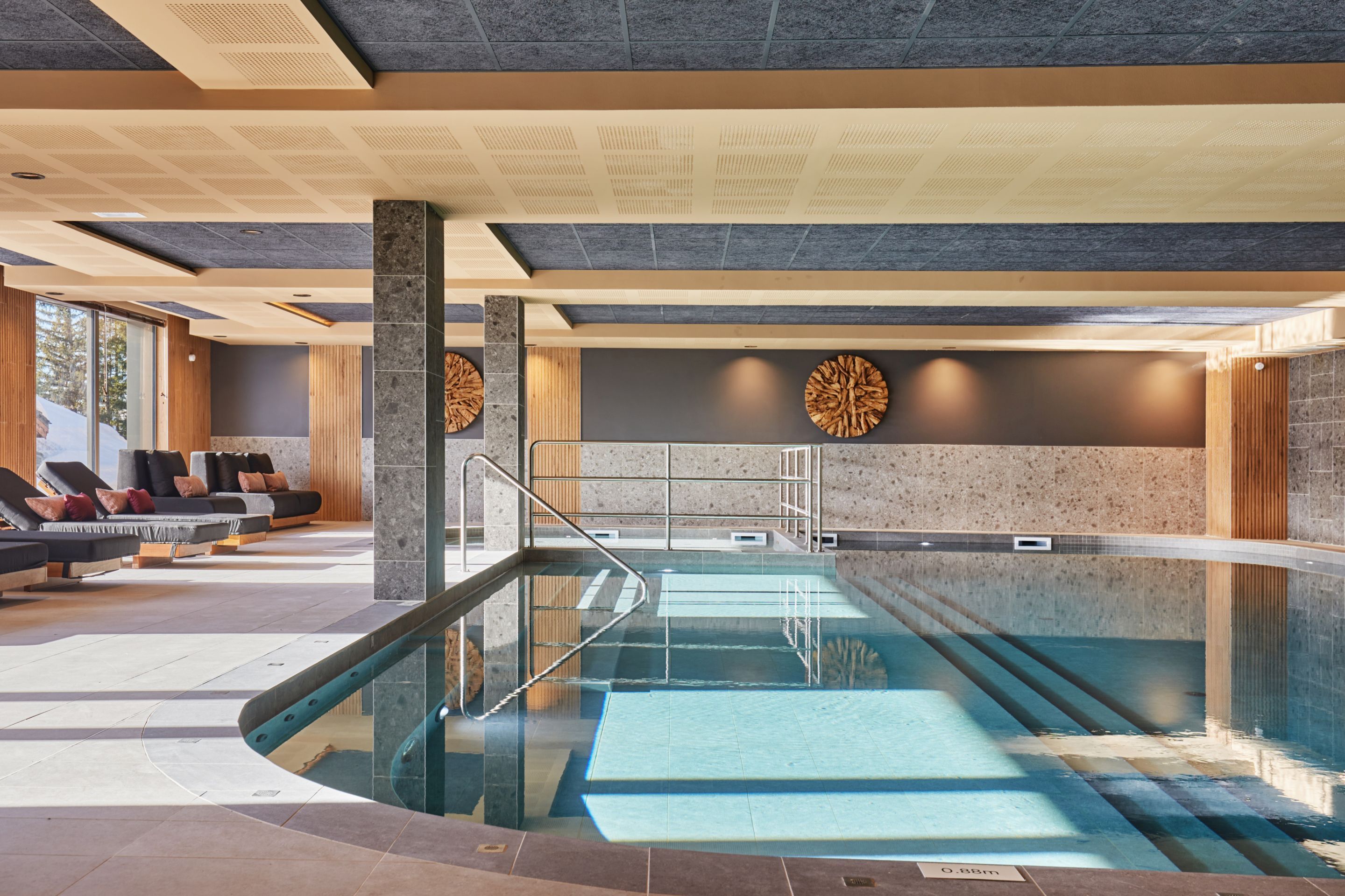 image Indoor heated pool with lounge chairs and large windows looking out to the snow-capped peaks — included in every stay.