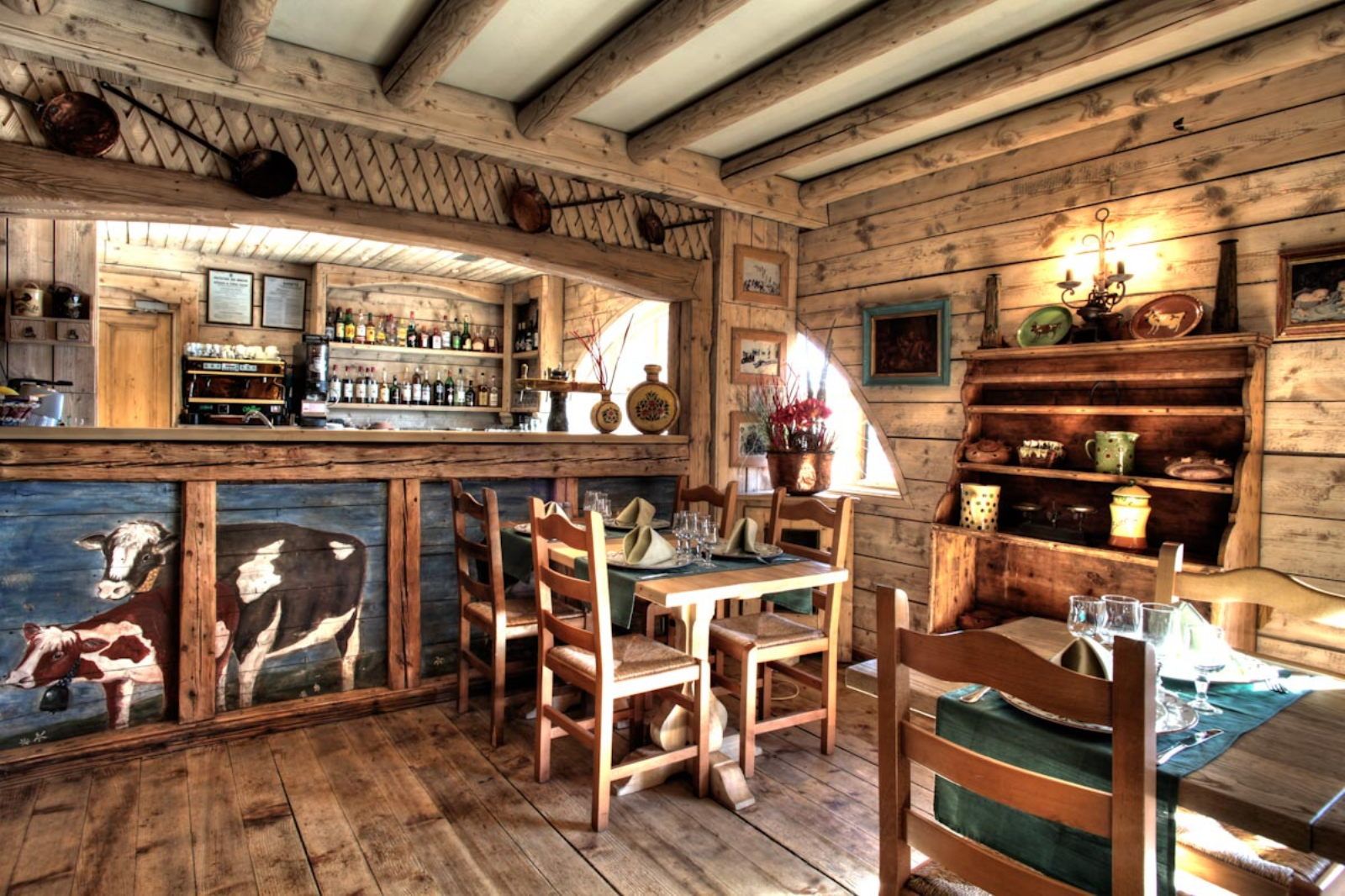 image A lively restaurant interior with painted cow murals and a bar — rustic charm at its best