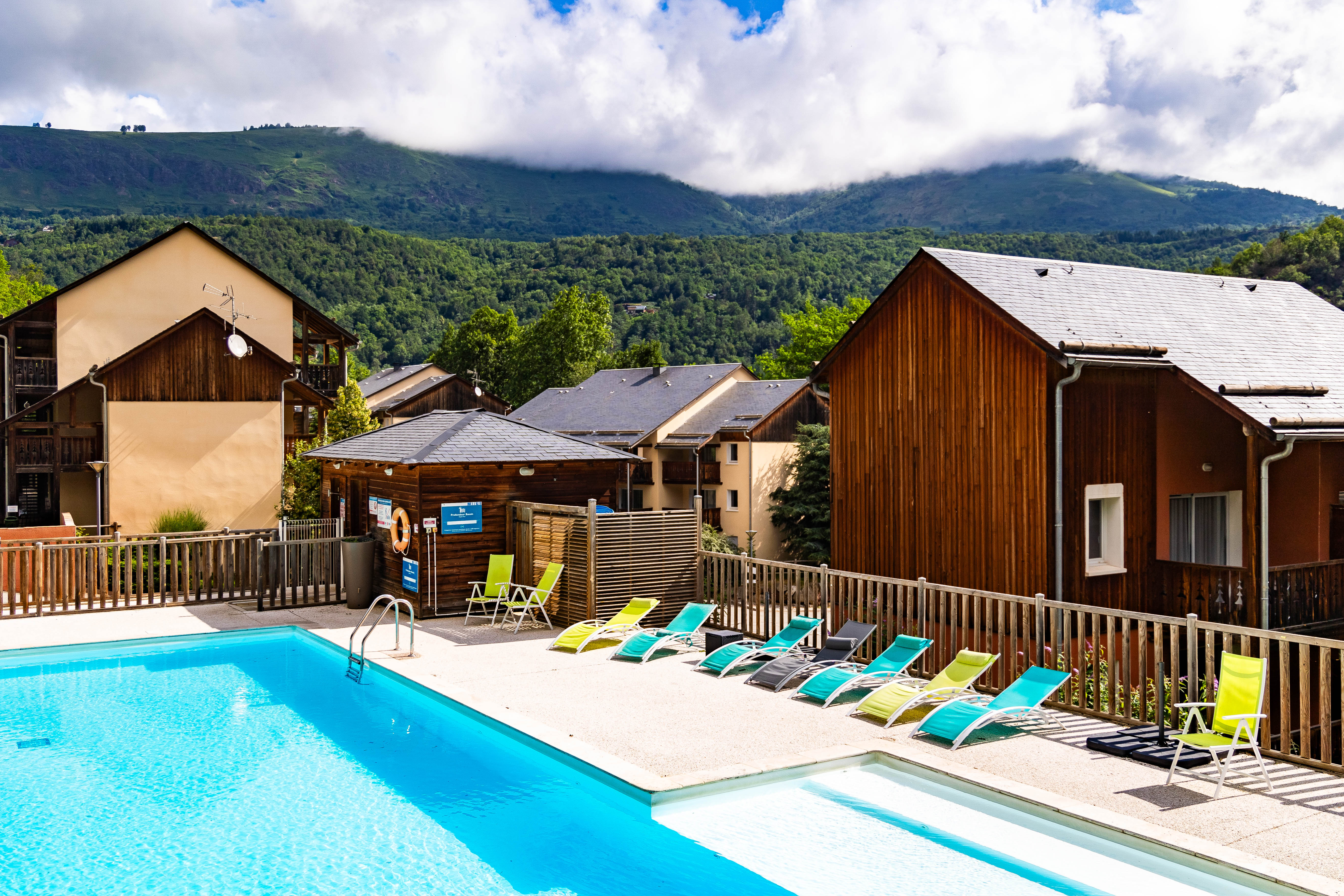 image Inviting seasonal pool framed by timber chalets and panoramic Pyrenean peaks.