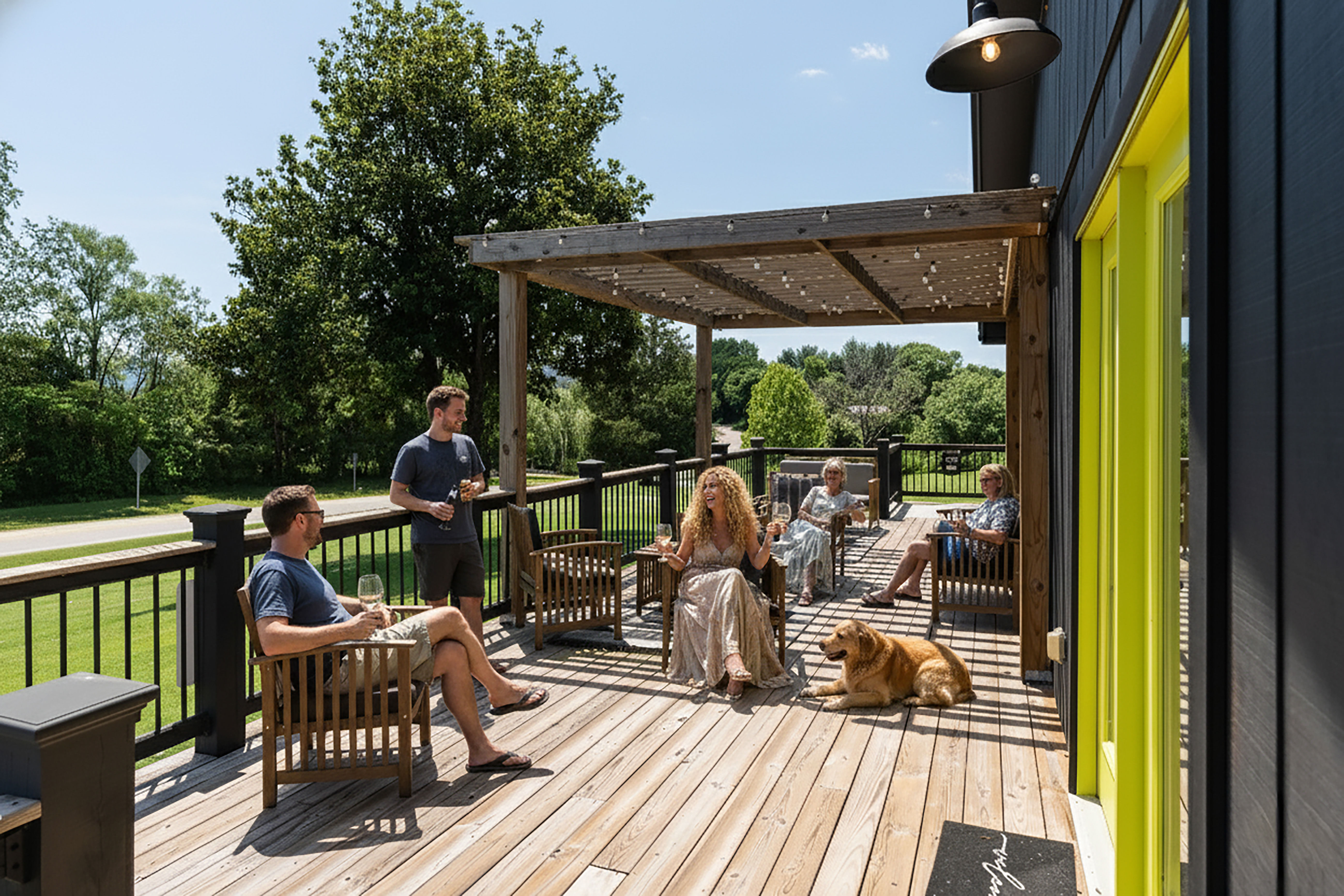 image Friends share wine and laughter on a sunny deck framed by lush countryside and warm wood accents.