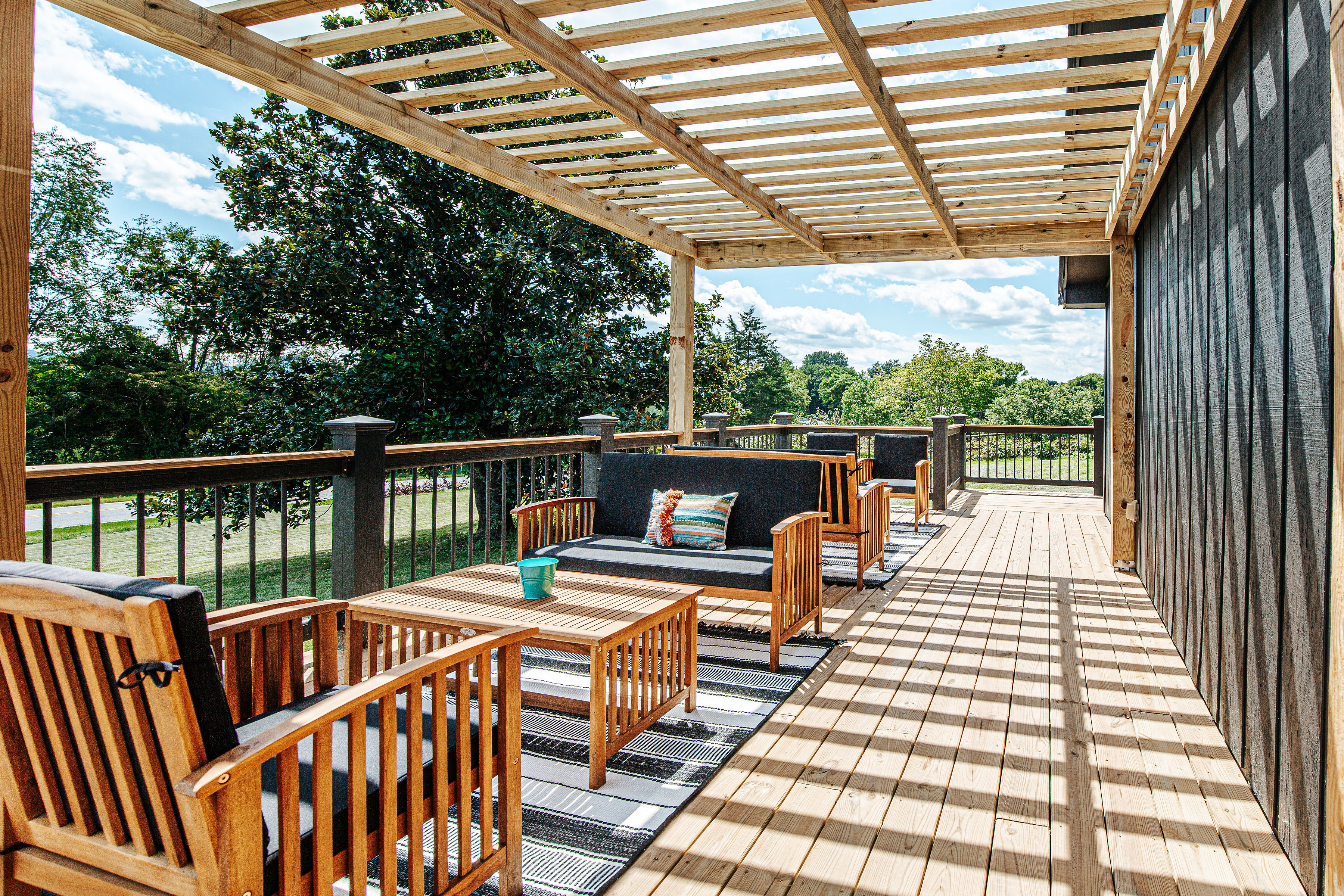 image Spacious deck with wooden seating and pergola.