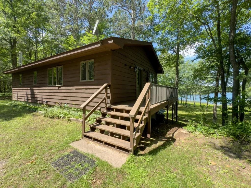 image This cabin showcases a wooden exterior with a spacious deck that leads into a lush yard, perfect for outdoor activities.
