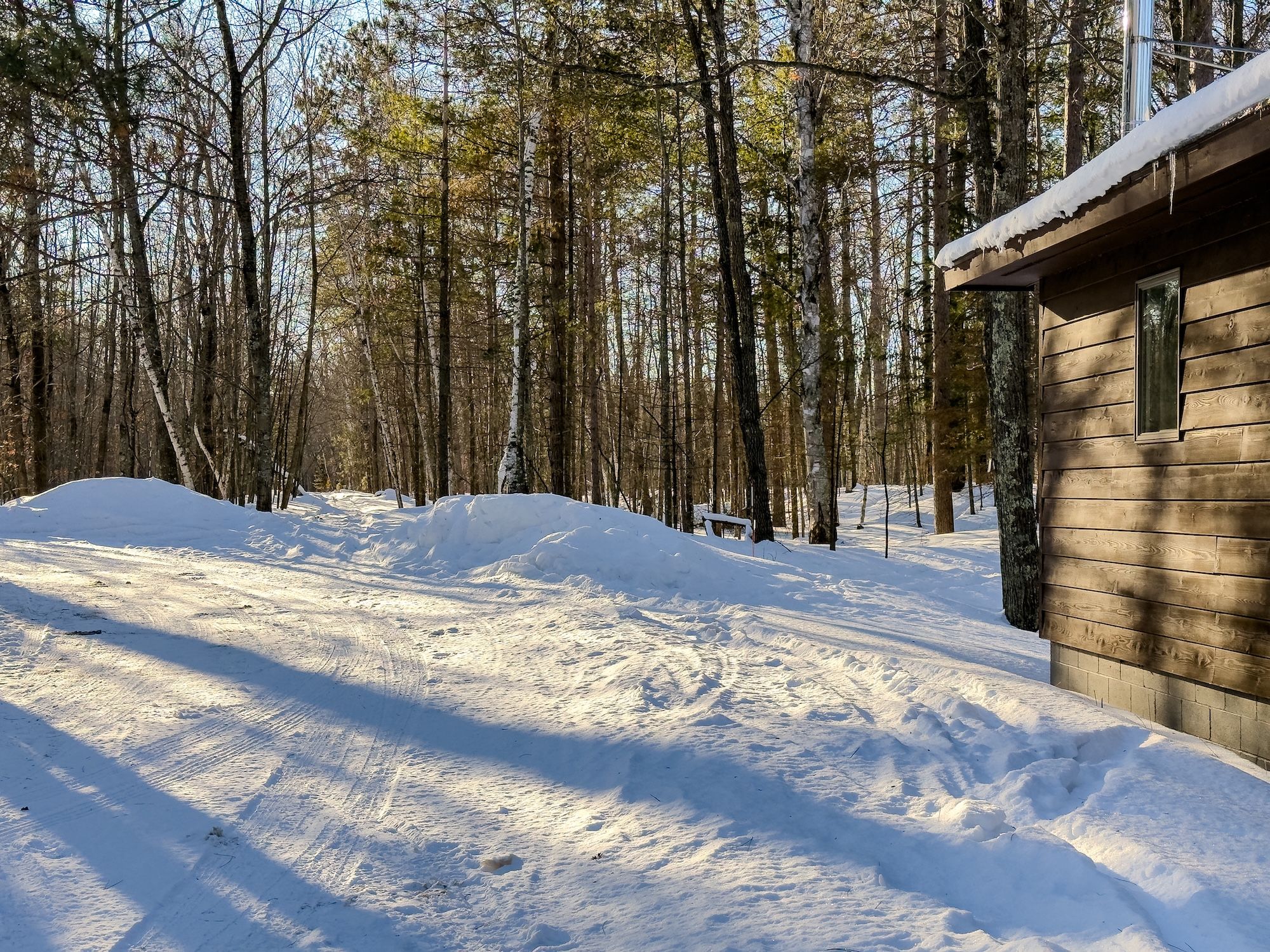 image A snow-covered path winds through tranquil woods, perfect for winter excursions and direct access to snowmobile trails.